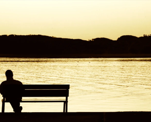 Mann auf Bank vor See