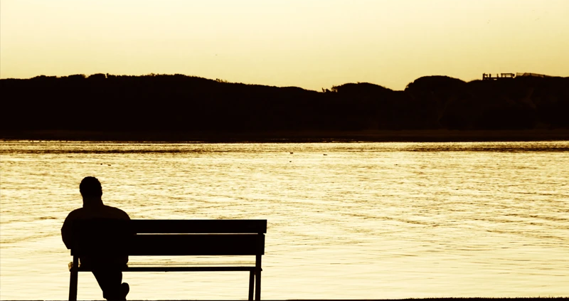 Mann auf Bank vor See