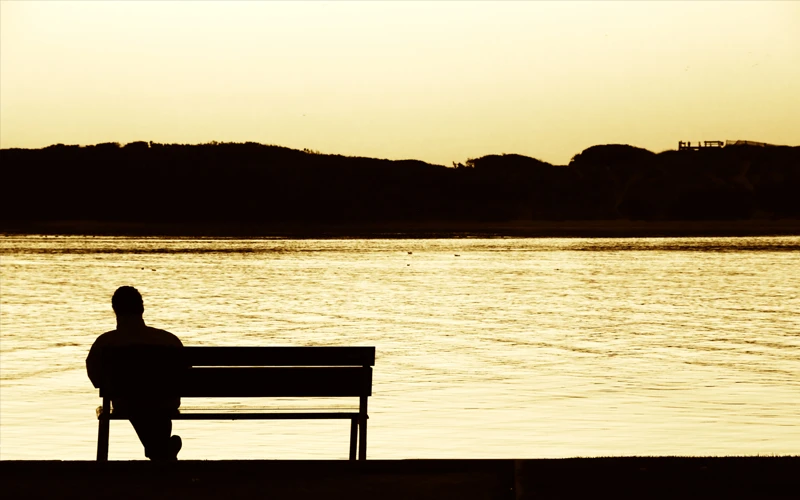 Mann auf Bank vor See